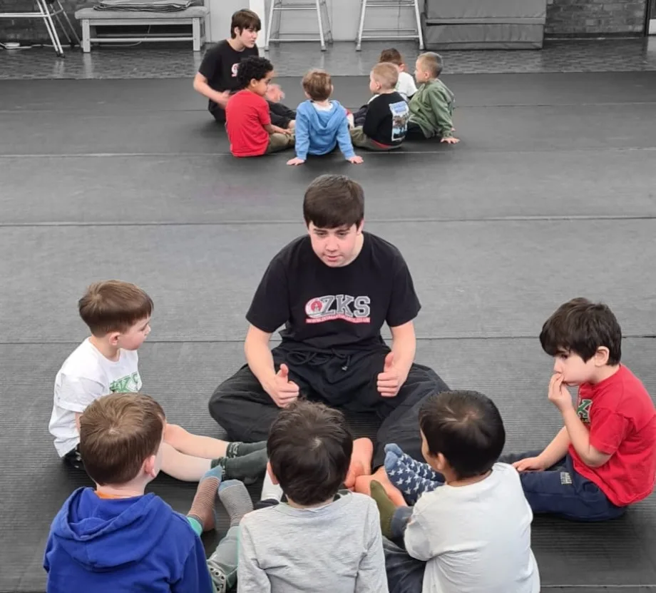 Little Dragons children sitting in groups with ZKS team members on the mats
