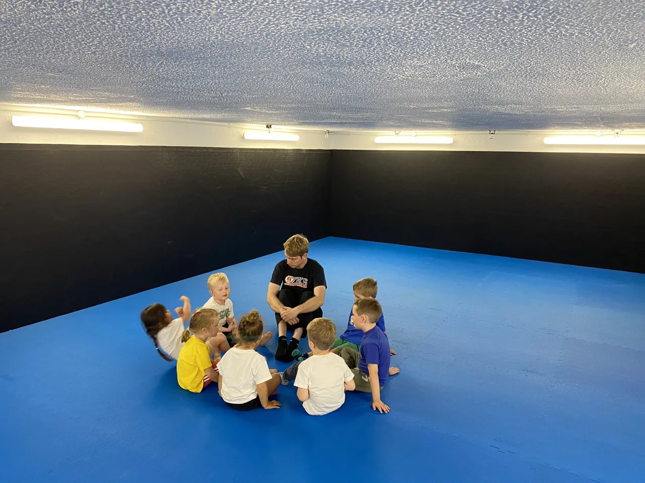 Little Dragons children seated in a circle with a ZKS team member