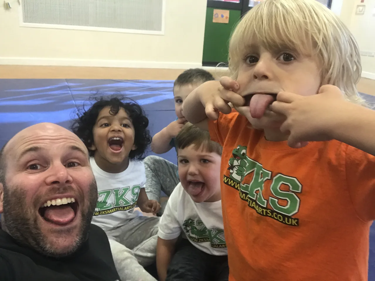 Little Dragons children and a ZKS team member pulling playful faces together