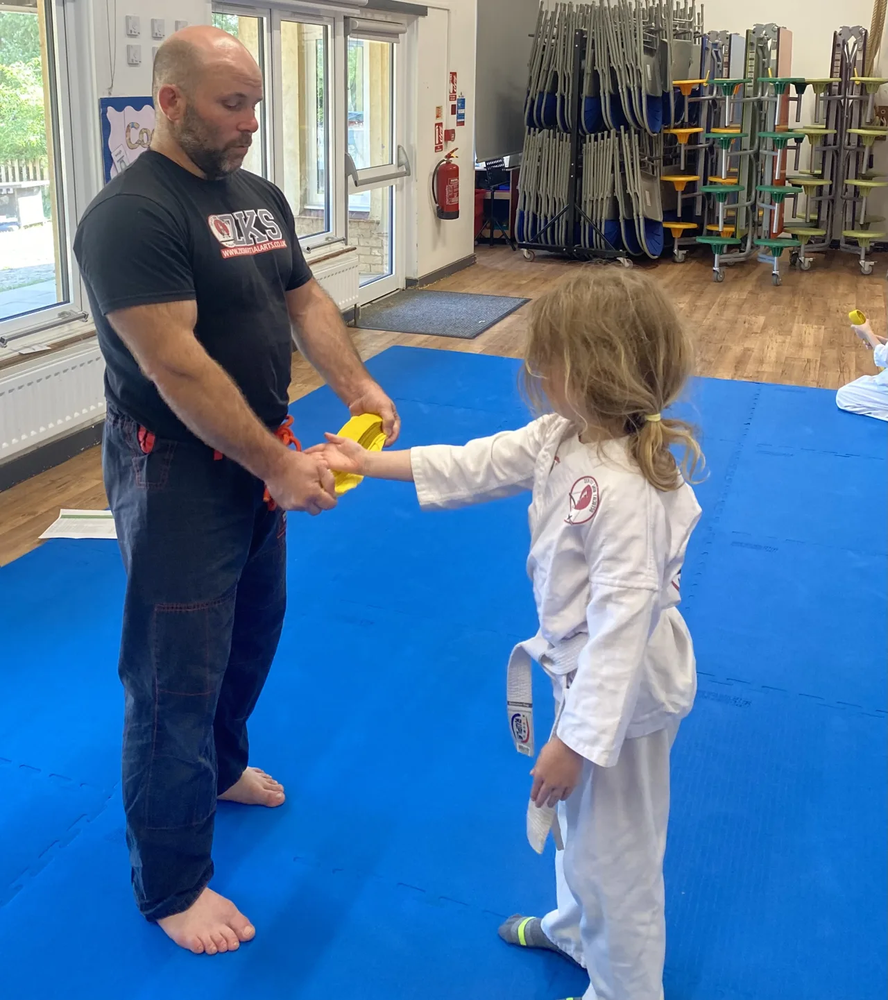 A Mini Ninjas child receiving a yellow belt from an instructor during class