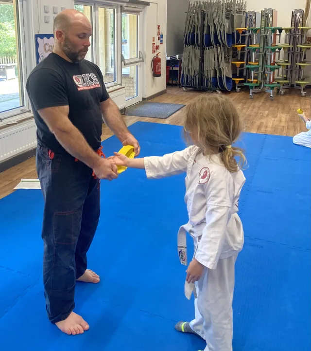 A ZKS instructor congratulates a young student during a belt presentation