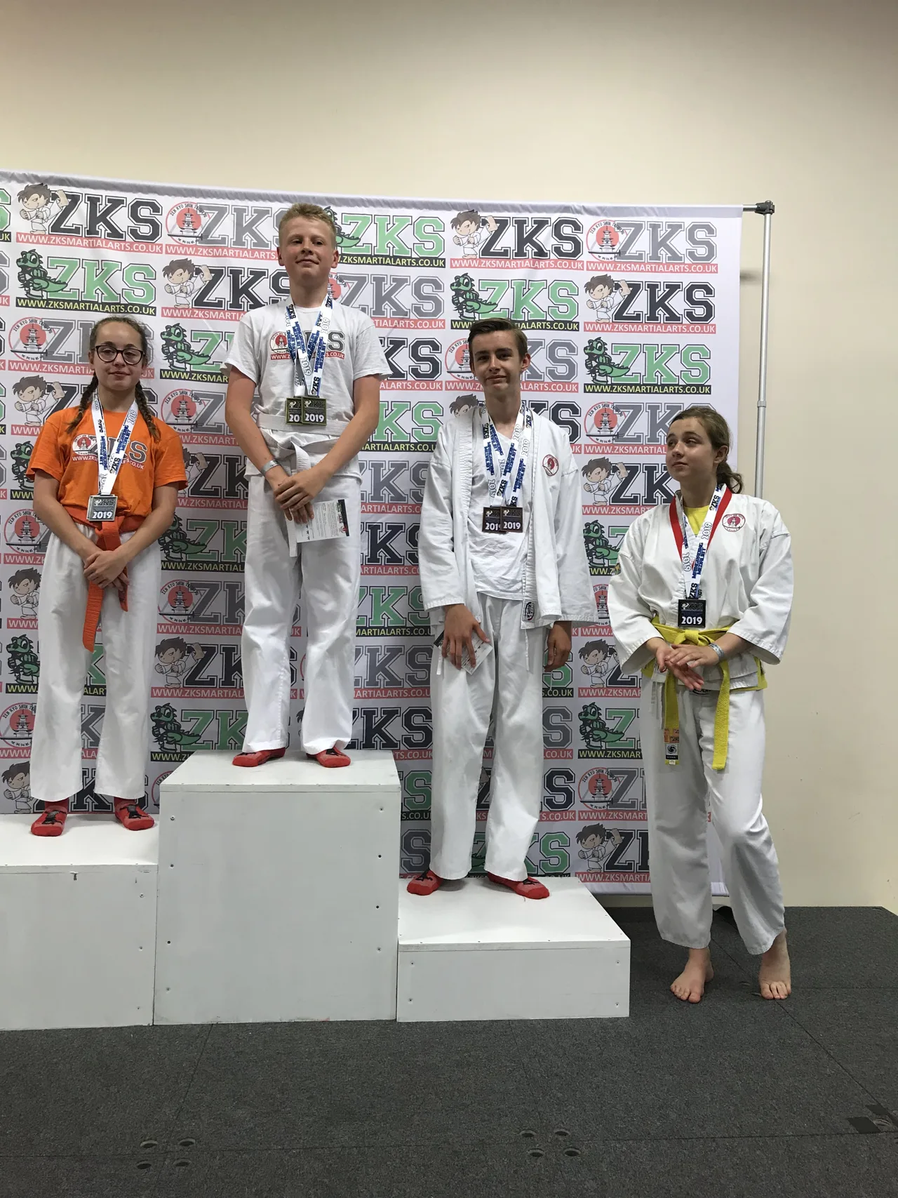 Four ZKS students wearing medals on a podium at a past event
